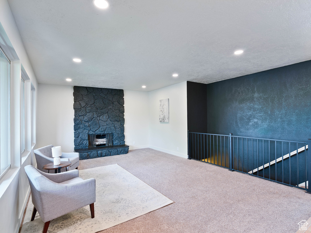 Living area featuring carpet, recessed lighting, a stone fireplace, and baseboards