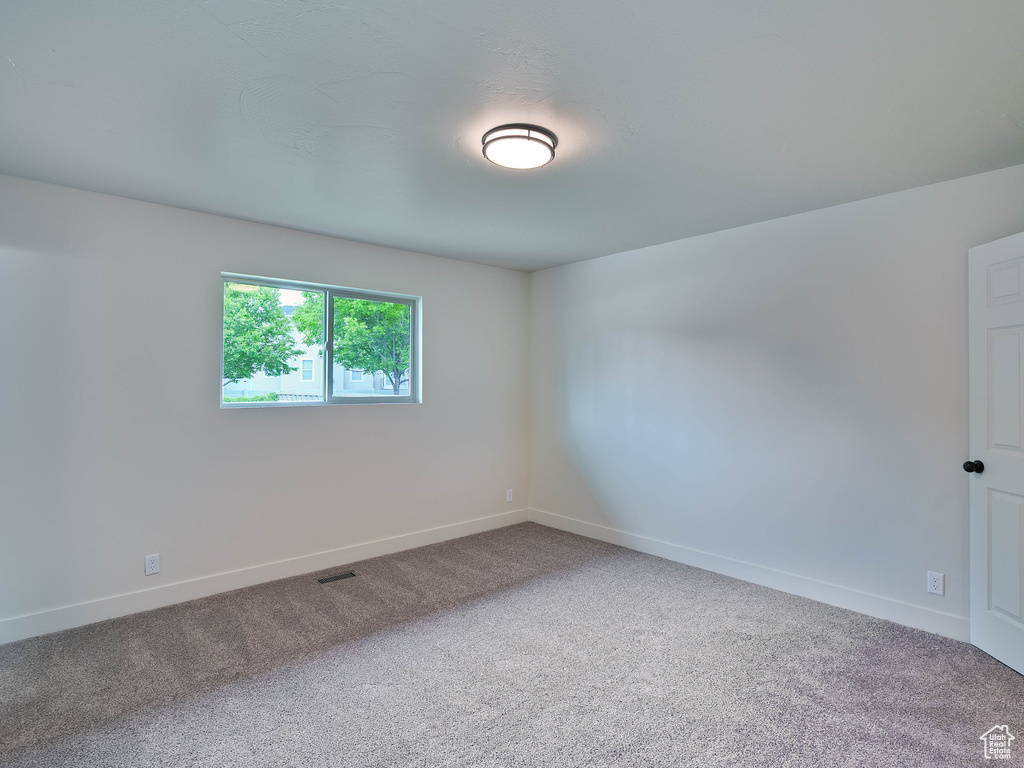 Spare room featuring carpet flooring and baseboards