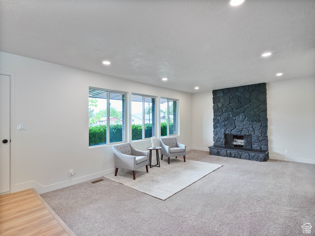 Living room featuring recessed lighting, baseboards, a stone fireplace, a textured ceiling, and carpet flooring