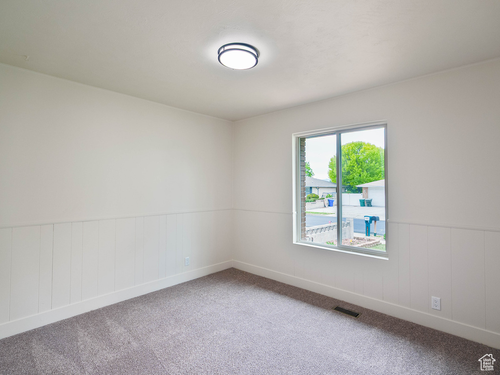Carpeted empty room featuring wainscoting