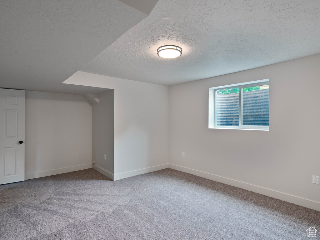 Spare room with a textured ceiling, baseboards, and carpet floors