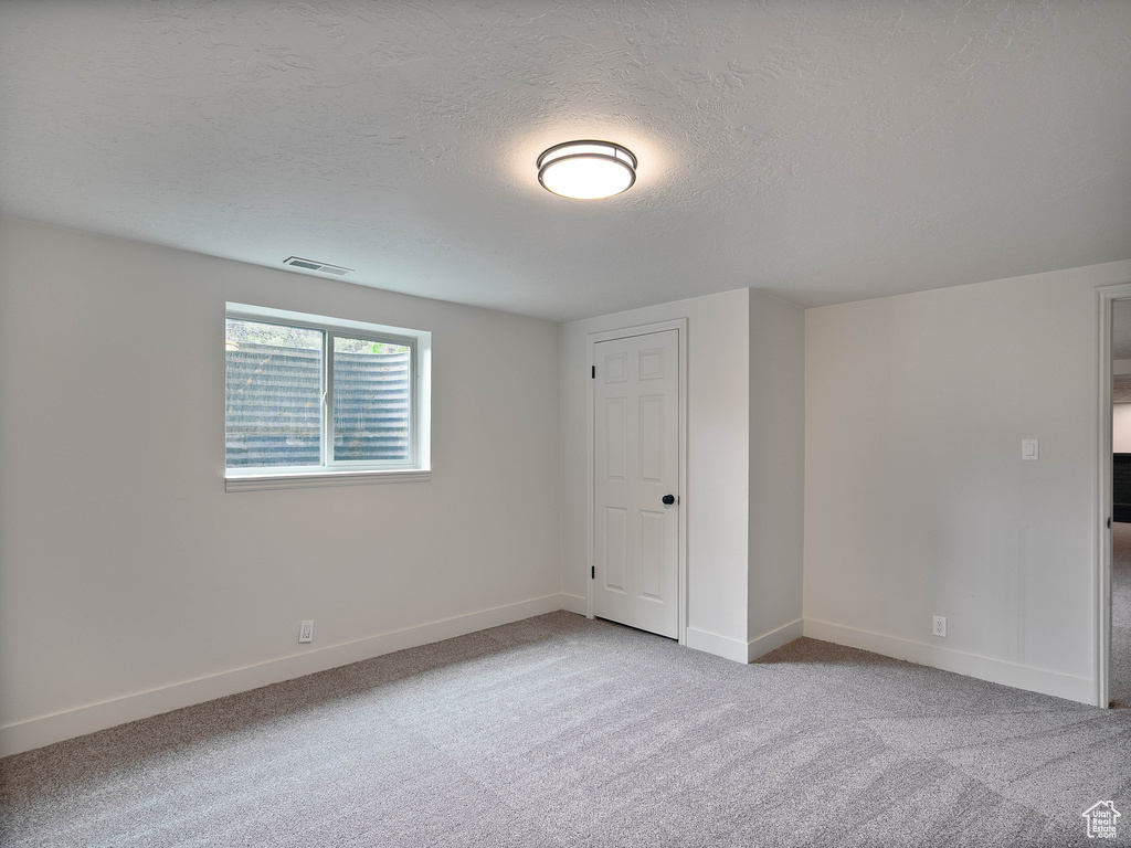 Unfurnished bedroom with carpet floors, baseboards, and a textured ceiling