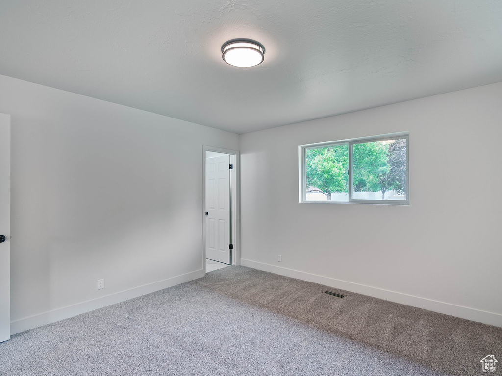 Spare room featuring carpet flooring and baseboards
