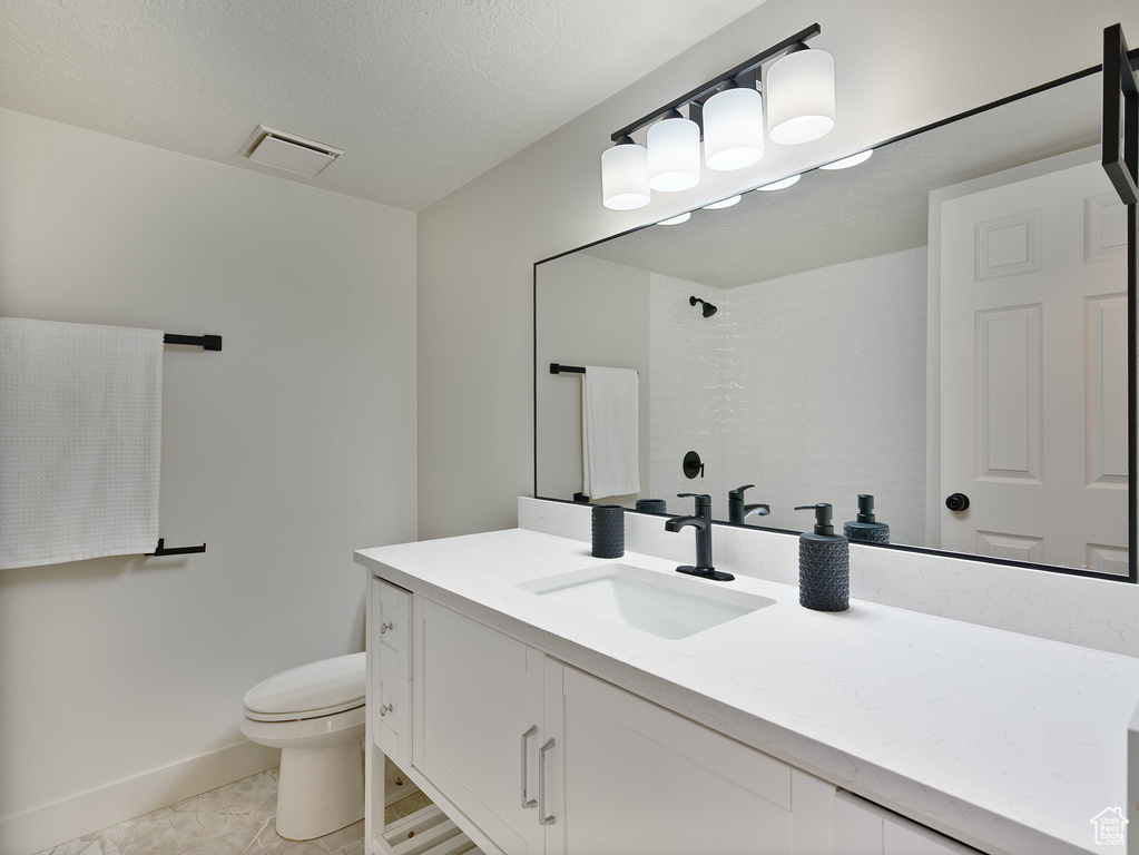 Full bath with toilet, vanity, a shower, and baseboards