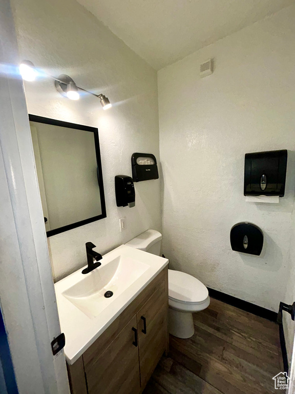Bathroom with wood finished floors, vanity, toilet, and baseboards