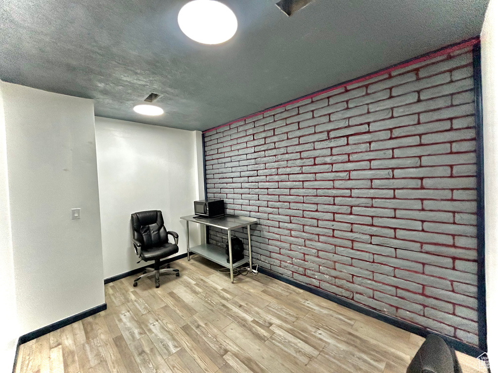 Office with brick wall, wood finished floors, and baseboards
