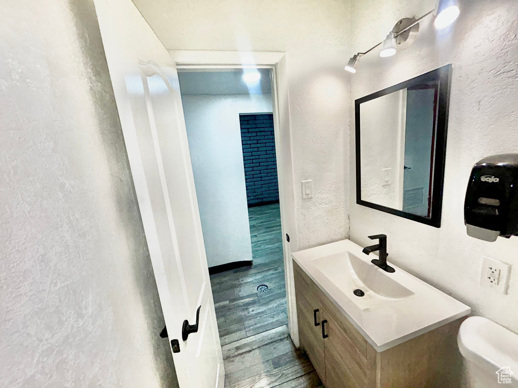 Bathroom featuring wood finished floors, toilet, vanity, and a textured wall