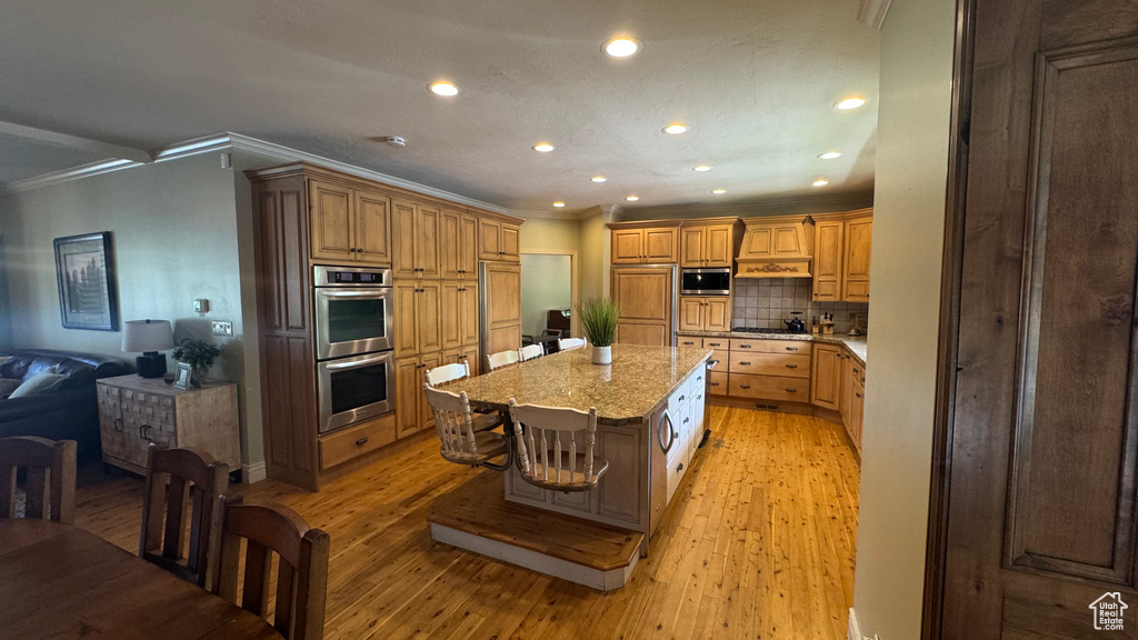 Kitchen featuring built in appliances, crown molding, recessed lighting, decorative backsplash, and light wood-style flooring