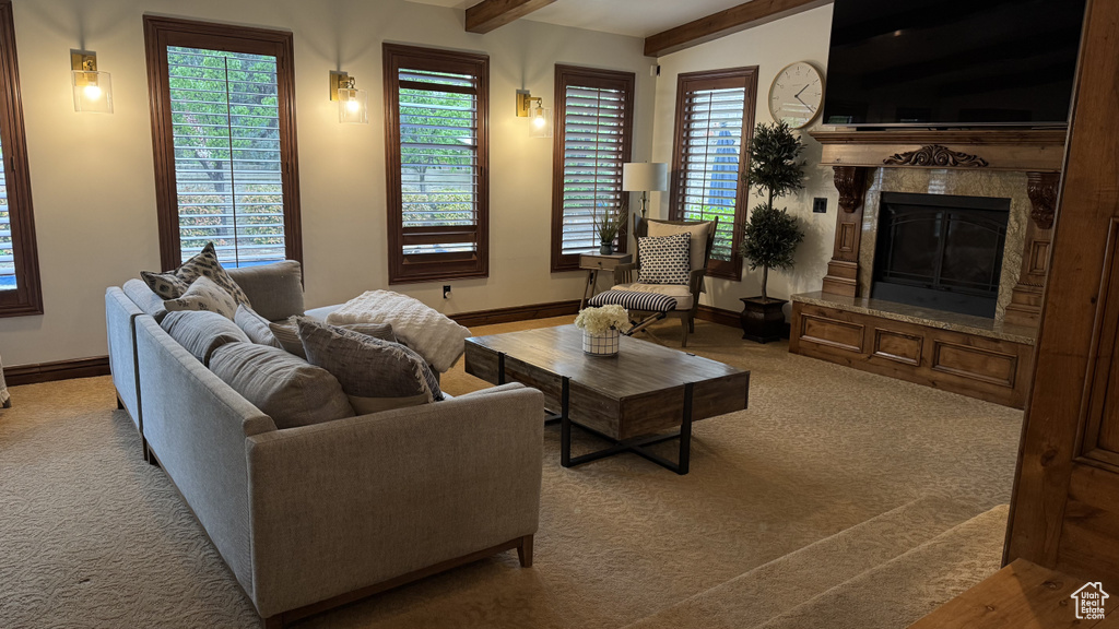 Carpeted living room with baseboards, beam ceiling, and a fireplace