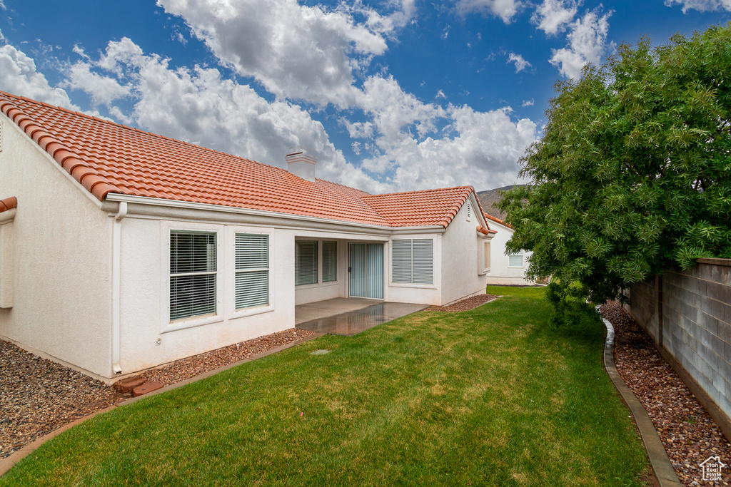 Rear view of property with a chimney, a tiled roof, stucco siding, and a patio area
