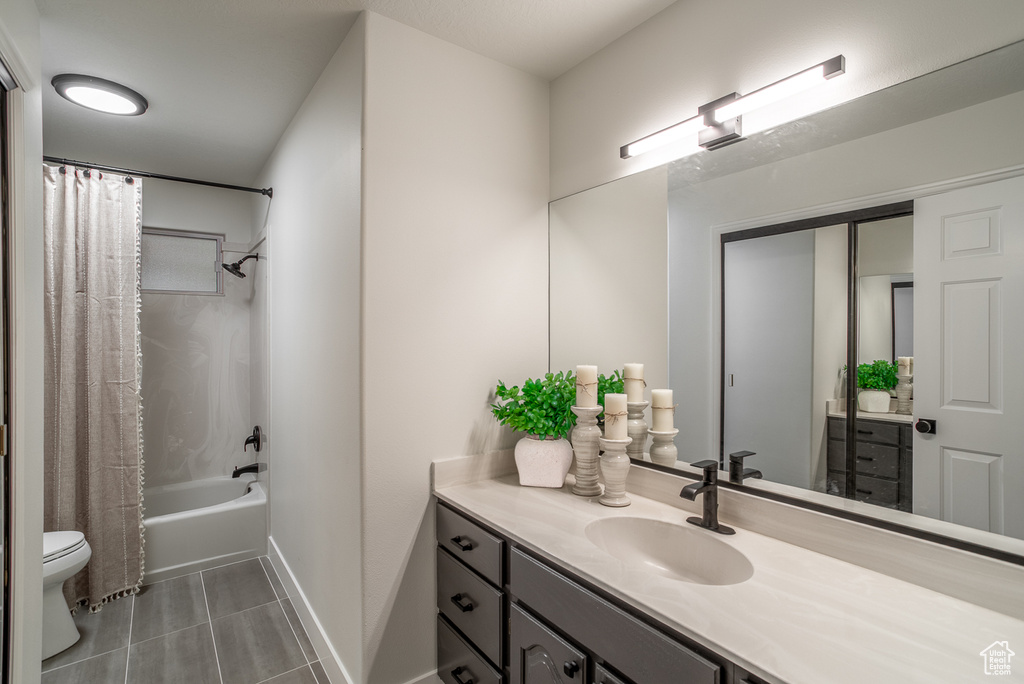 Bathroom featuring toilet, shower / tub combo with curtain, vanity, tile patterned flooring, and baseboards