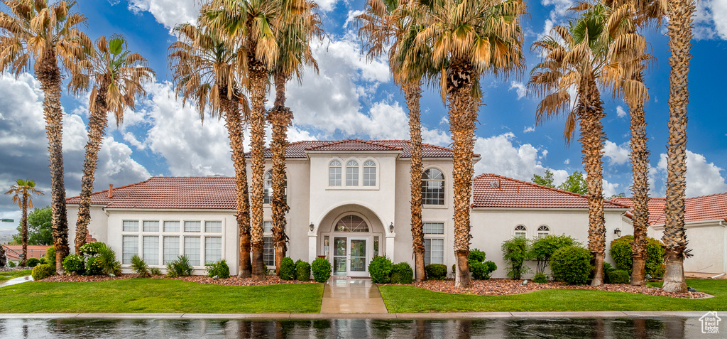 Mediterranean / spanish-style house with a tile roof, stucco siding, a front lawn, and french doors