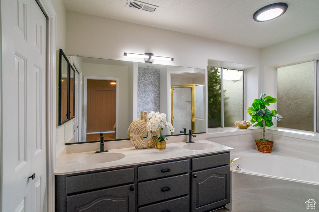 Full bathroom featuring a shower stall, double vanity, and a garden tub