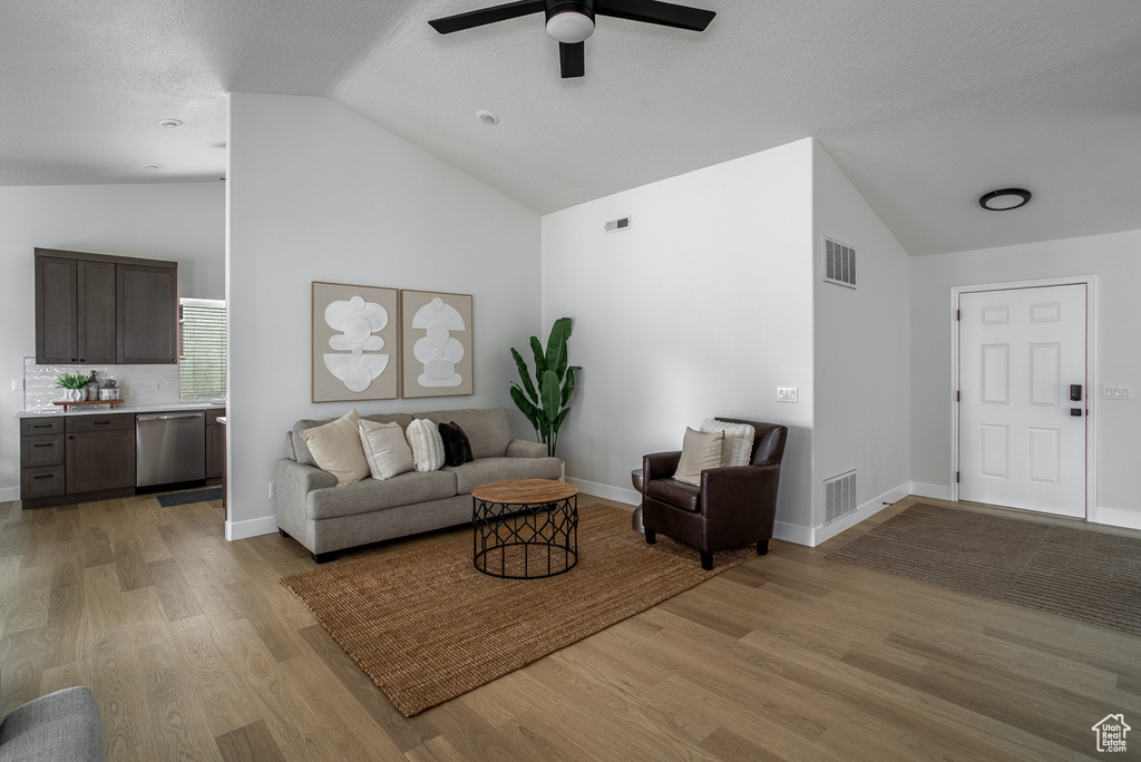 Living area with a ceiling fan, light wood-type flooring, high vaulted ceiling, and baseboards