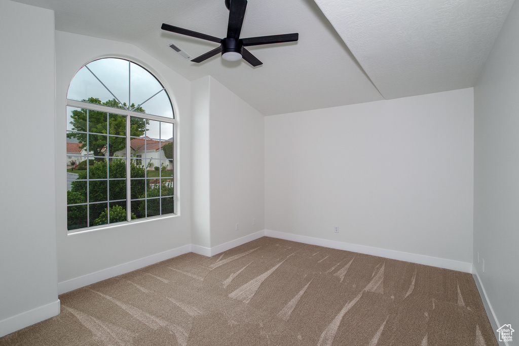 Spare room with carpet, a ceiling fan, lofted ceiling, and baseboards
