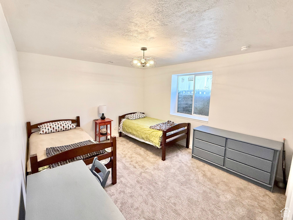 Carpeted bedroom with a chandelier and a textured ceiling