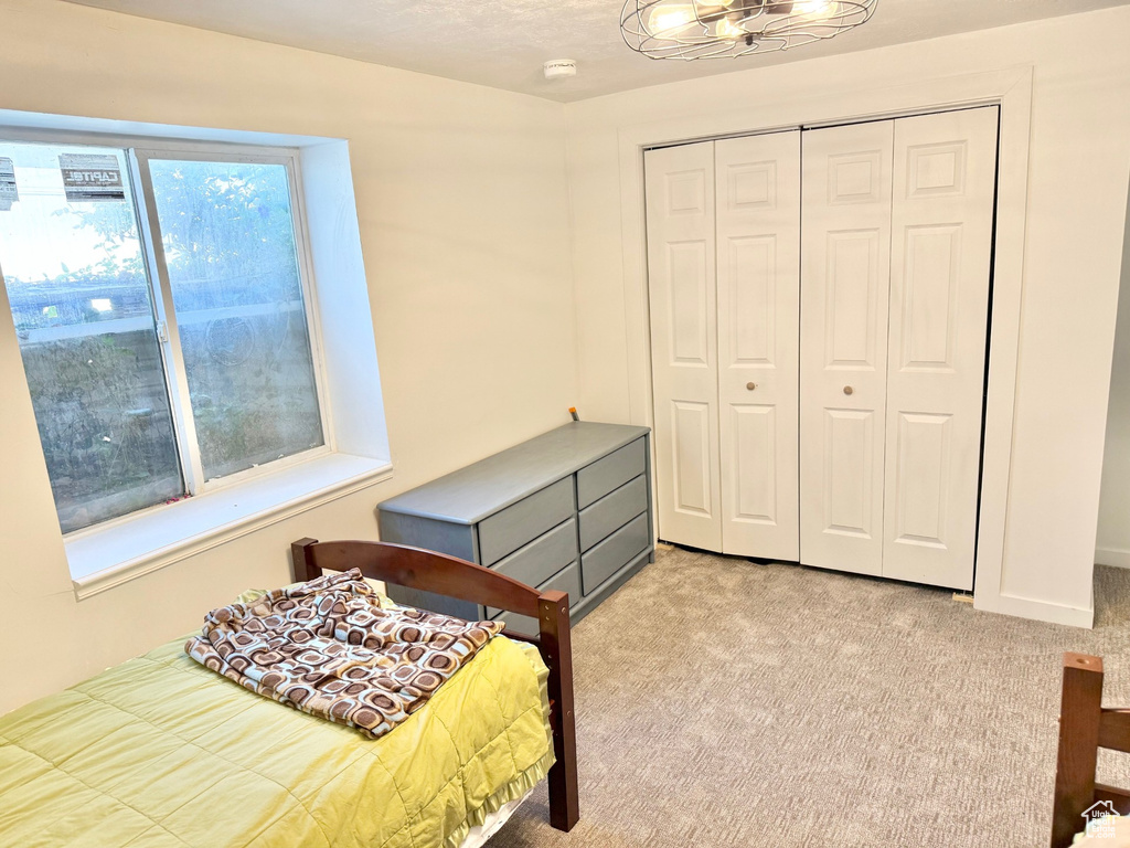 Bedroom with light carpet, a chandelier, and a closet