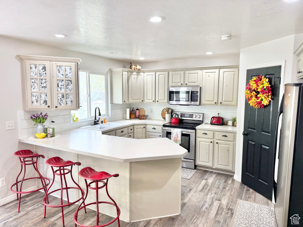 Kitchen featuring stainless steel appliances, a sink, a peninsula, a breakfast bar, and backsplash