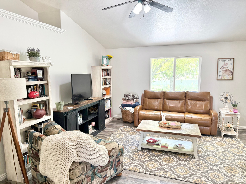 Living area with ceiling fan, wood finished floors, baseboards, and vaulted ceiling