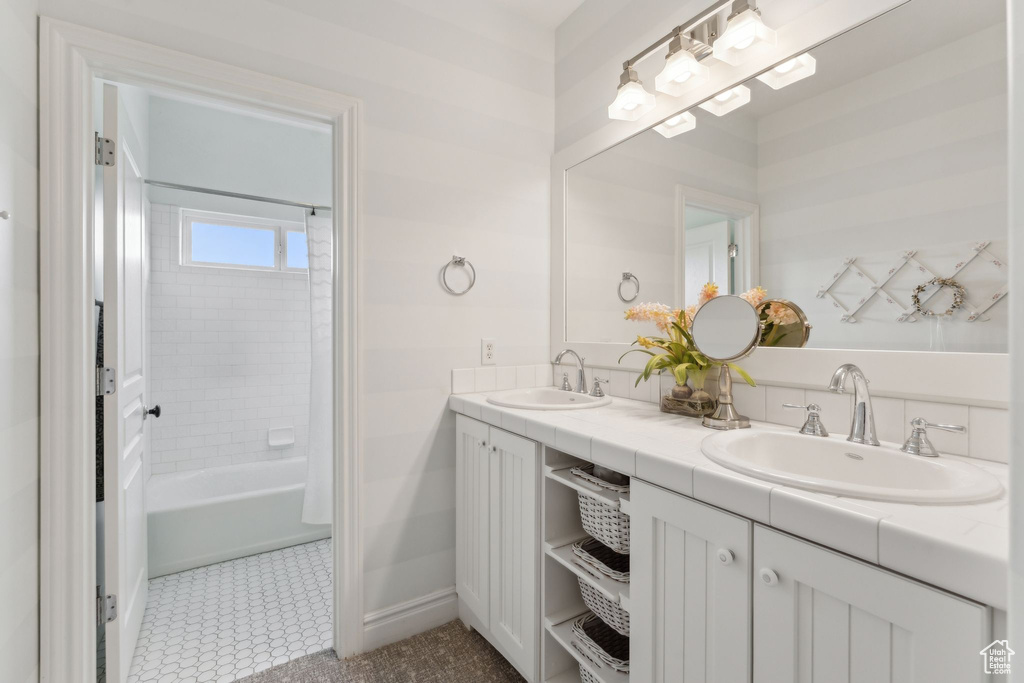 Bathroom with double vanity, baseboards, tile patterned floors, and shower / bathtub combination
