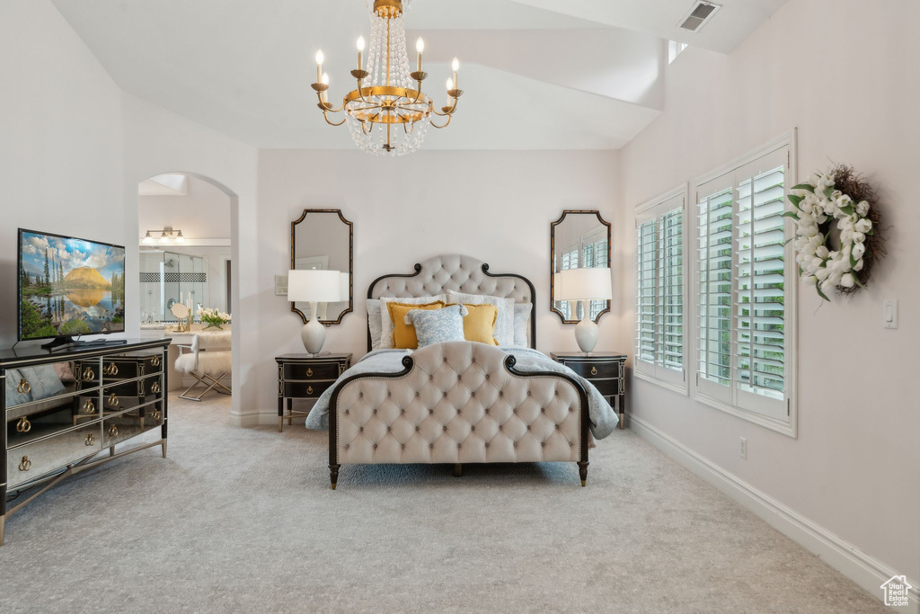 Carpeted bedroom featuring a chandelier, arched walkways, and baseboards