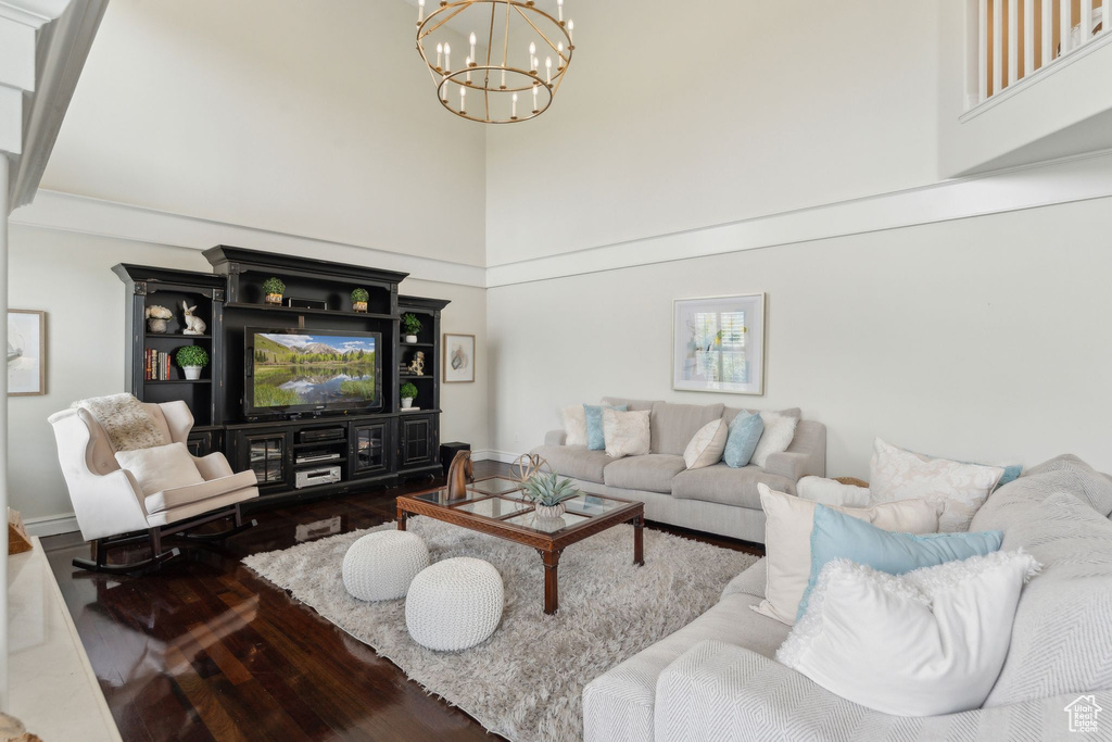 Living area with a high ceiling, a chandelier, wood finished floors, and baseboards