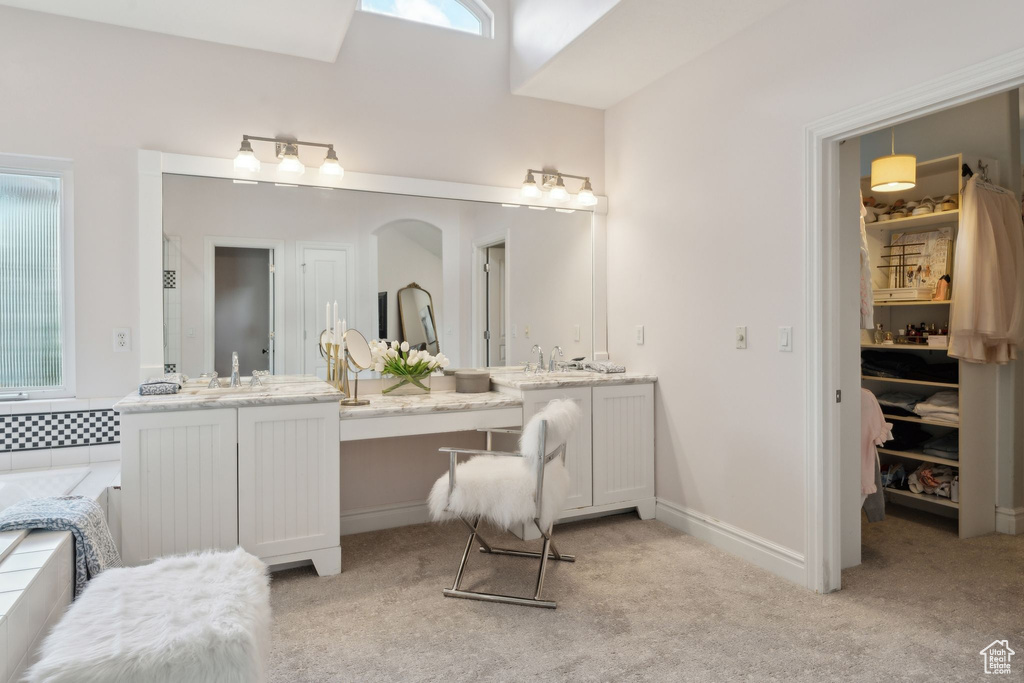 Bathroom with vanity, a garden tub, baseboards, and a spacious closet