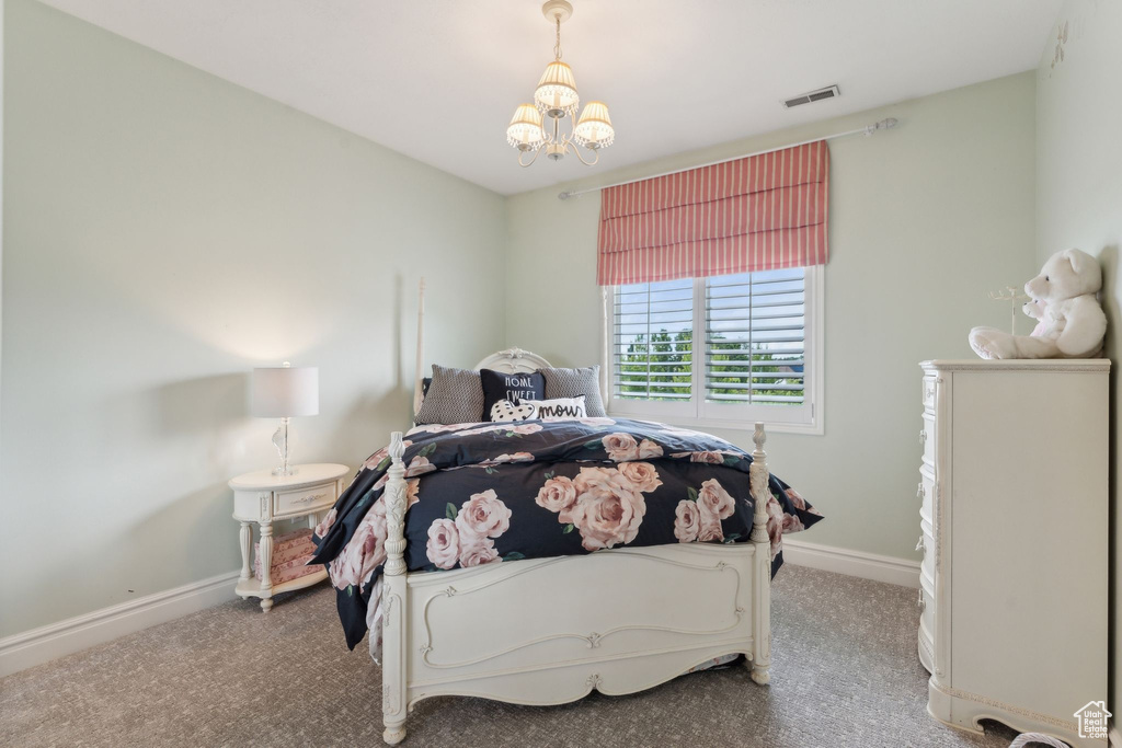 Carpeted bedroom with a chandelier and baseboards