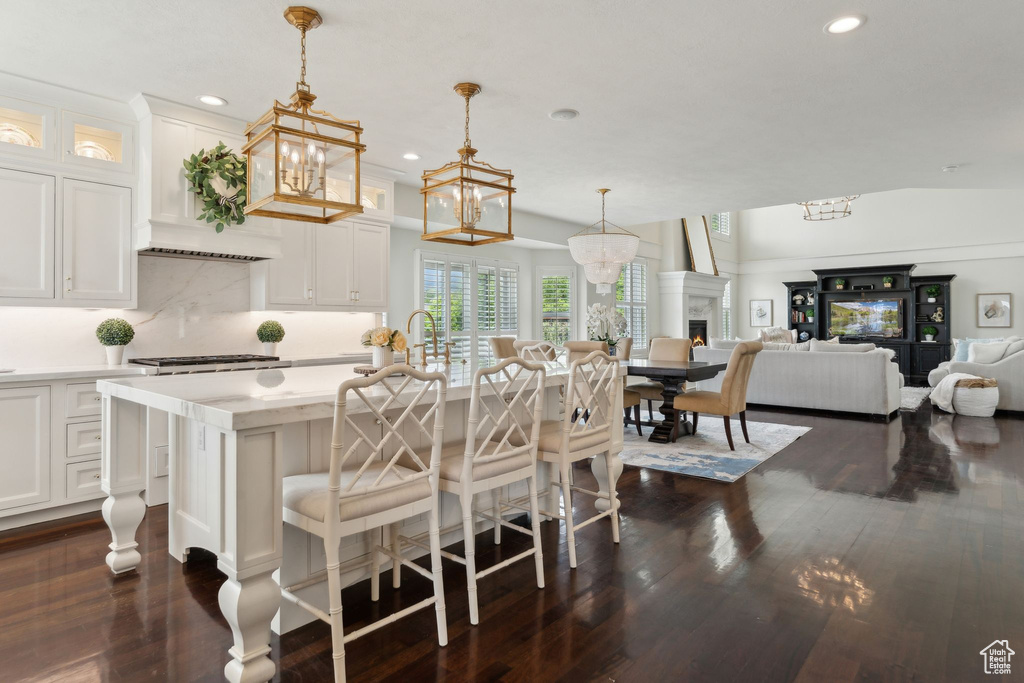 Kitchen with light countertops, dark wood-style flooring, white cabinets, recessed lighting, and a kitchen bar