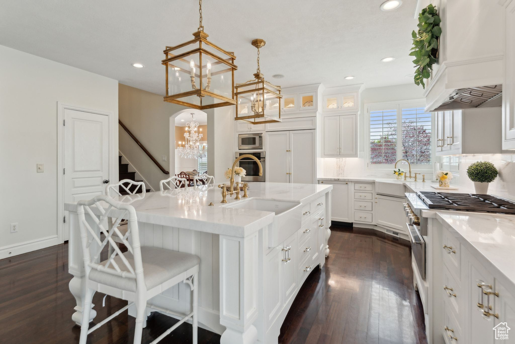 Kitchen with a chandelier, stainless steel appliances, custom range hood, a sink, and dark wood-style flooring