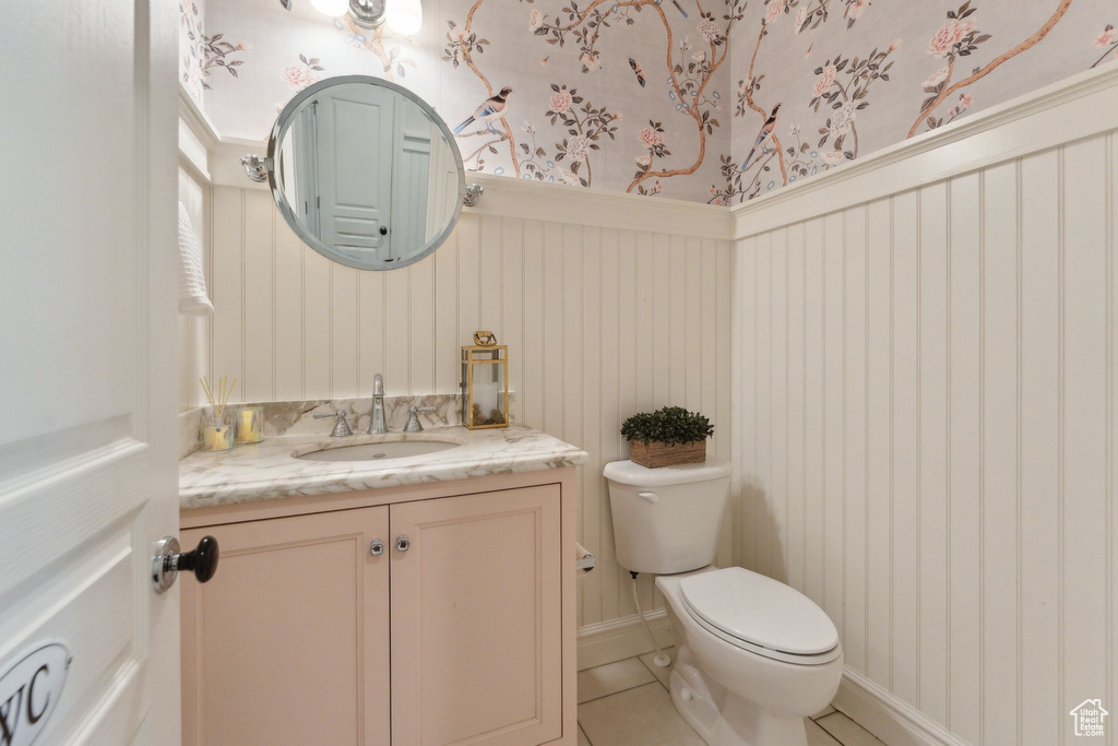 Bathroom featuring wallpapered walls, toilet, vanity, and tile patterned flooring
