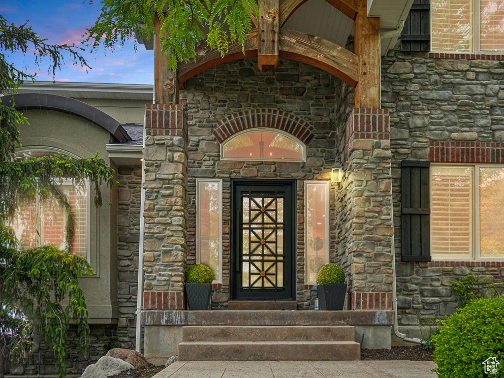 Exterior entry at dusk featuring stone siding
