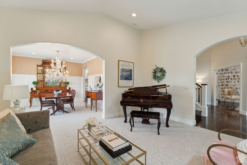 Living area with arched walkways, stairs, vaulted ceiling, recessed lighting, and carpet