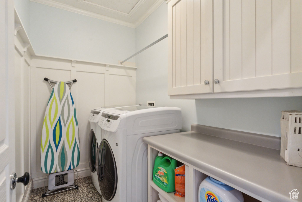 Clothes washing area featuring independent washer and dryer, ornamental molding, and cabinet space