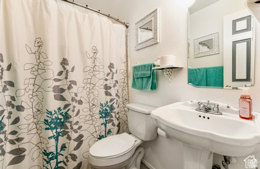 Bathroom featuring toilet and curtained shower