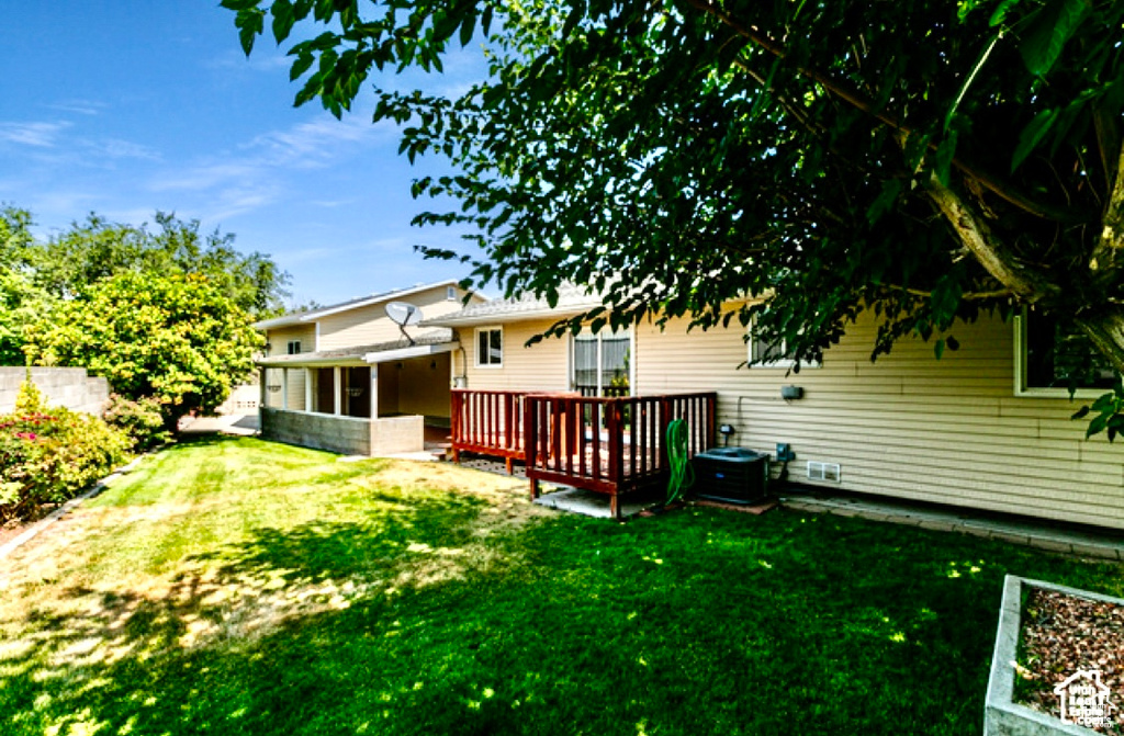 View of green lawn with a deck, a sunroom, and central AC