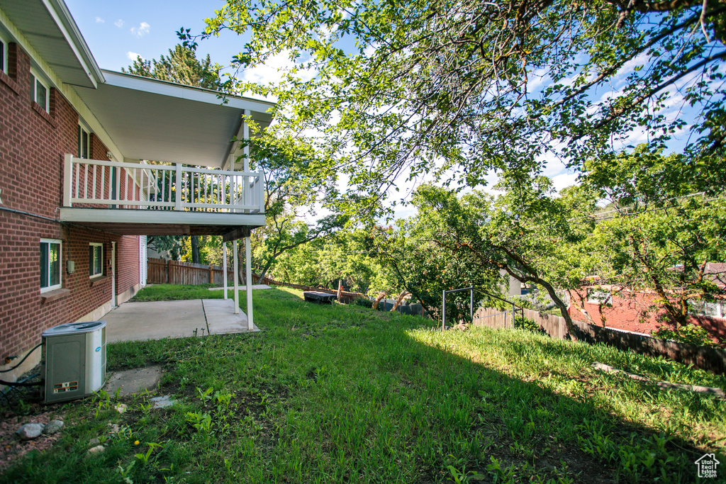 View of yard featuring a patio, a balcony, and central AC unit