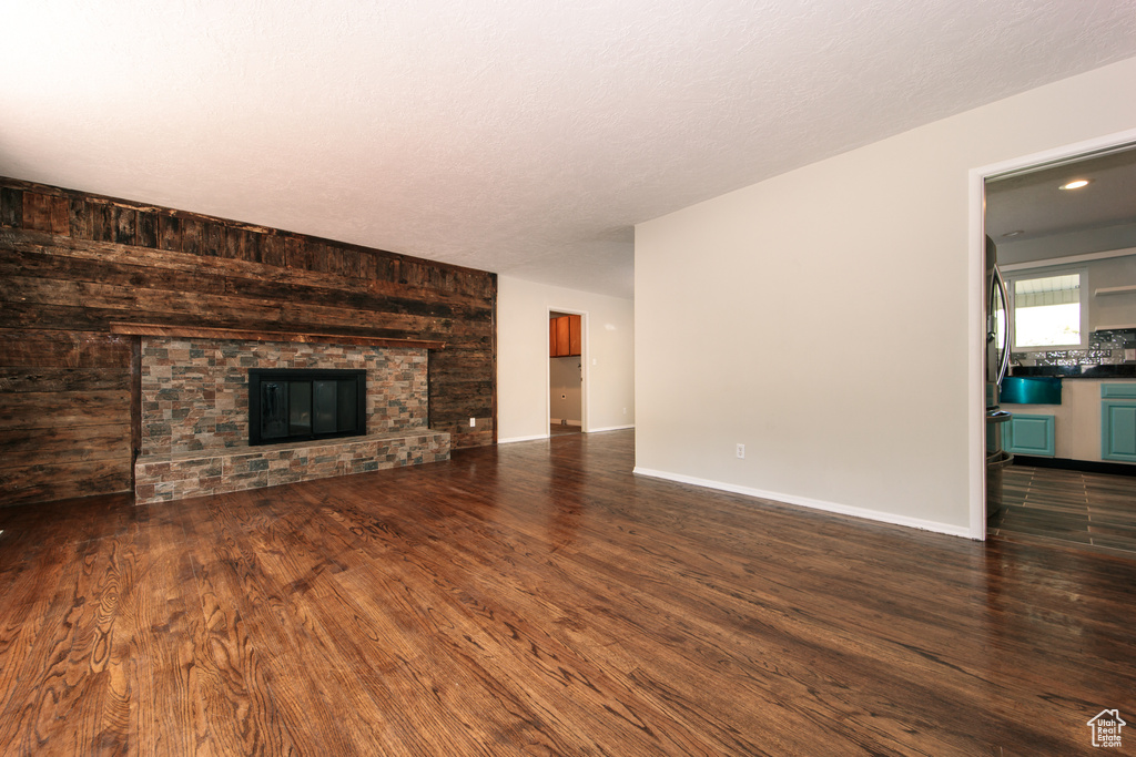 Unfurnished living room featuring dark wood-style floors, a large fireplace, and baseboards
