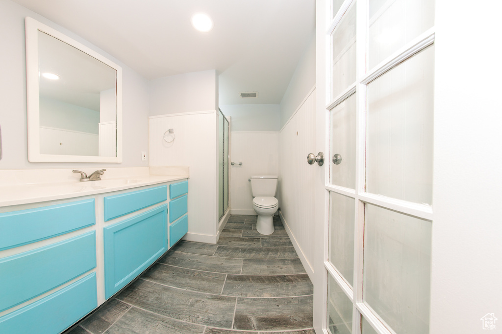Full bath with vanity, a shower stall, toilet, and wood finished floors