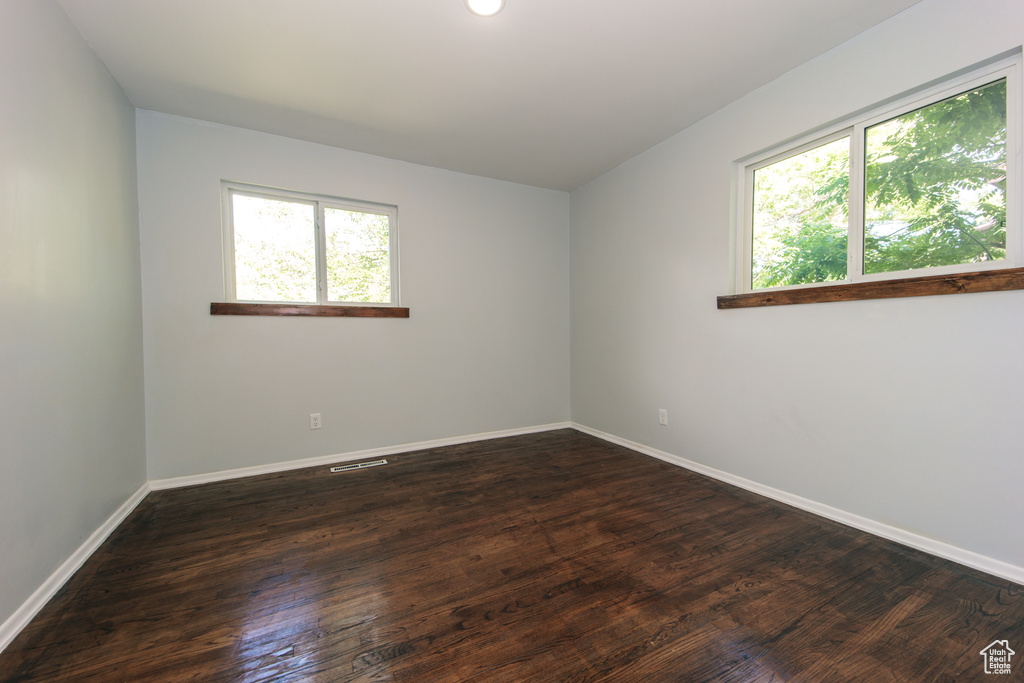 Empty room featuring baseboards and dark wood-style floors