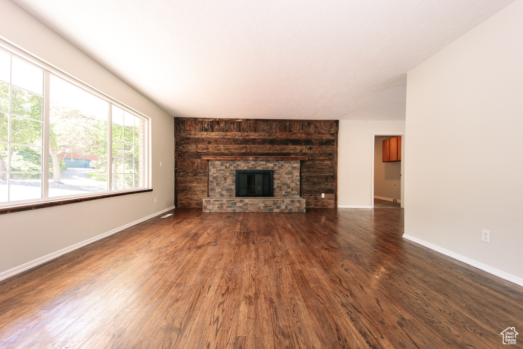 Unfurnished living room with wood finished floors, a fireplace, and baseboards