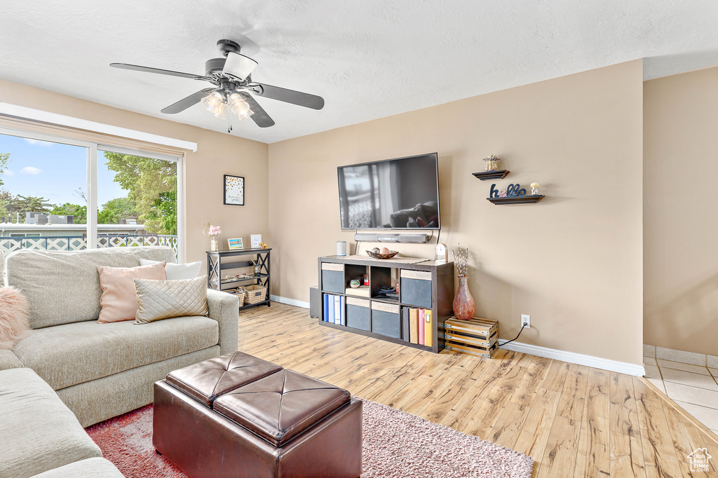 Living room featuring baseboards, wood finished floors, a ceiling fan, and a textured ceiling