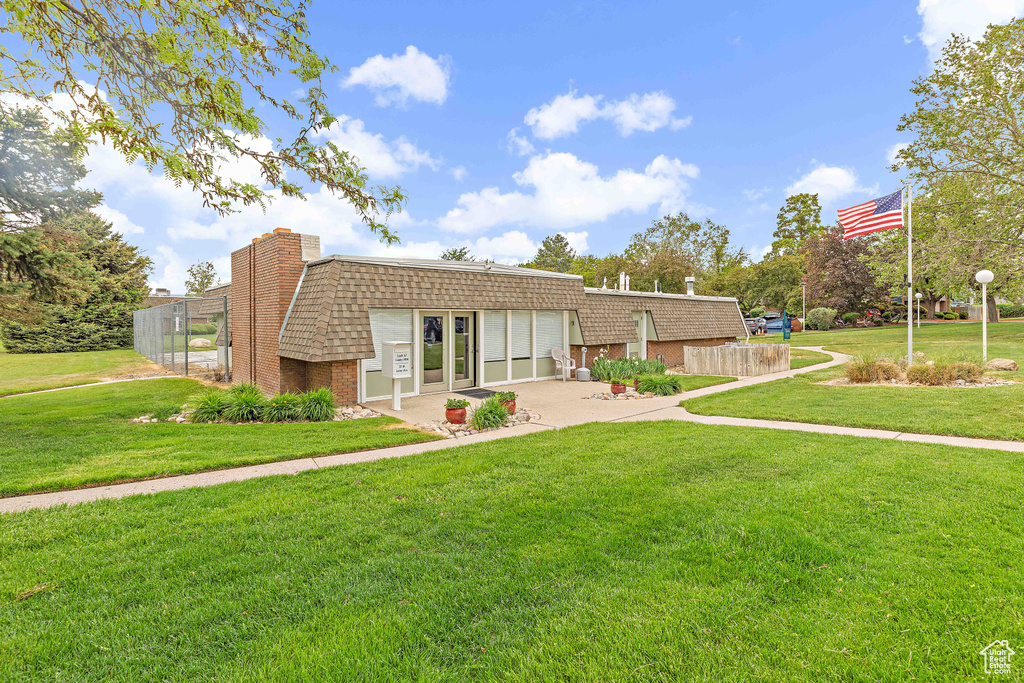Back of property with mansard roof, brick siding, driveway, and an attached garage