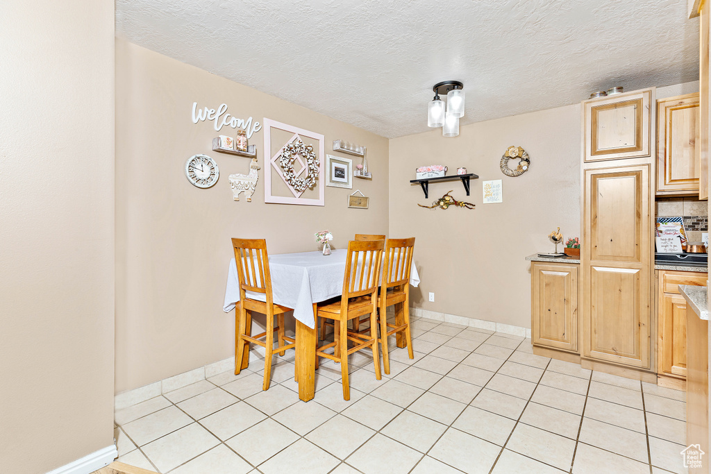 Dining space featuring light tile patterned floors, a textured ceiling, and baseboards