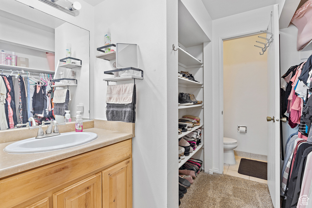 Bathroom featuring a spacious closet, tile patterned flooring, toilet, and vanity