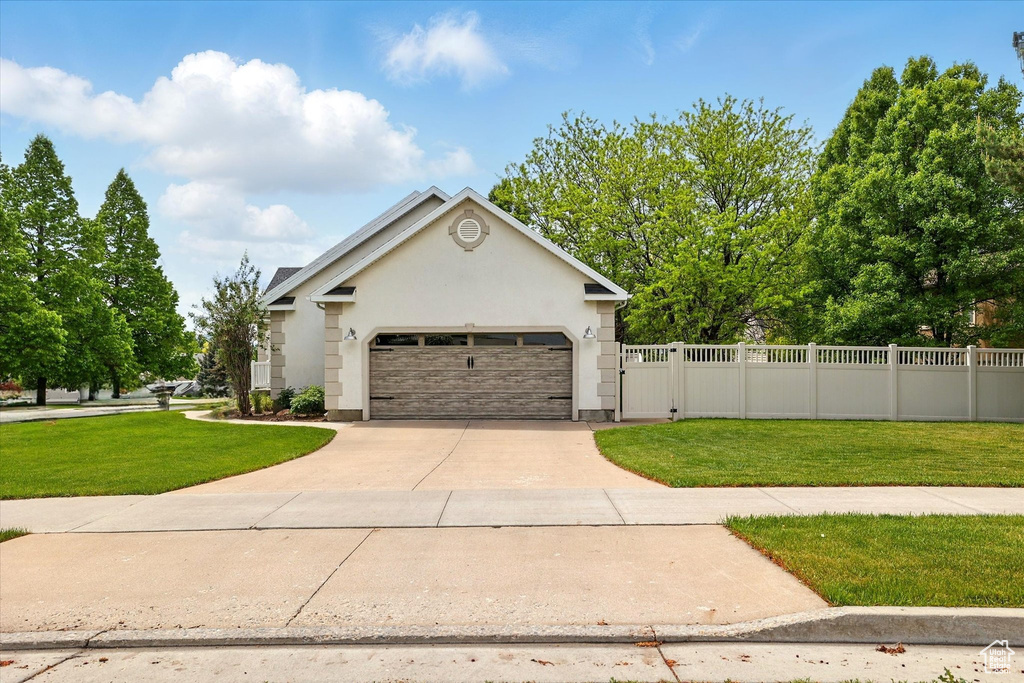 View of front of home with driveway, a garage, stucco siding, and a gate