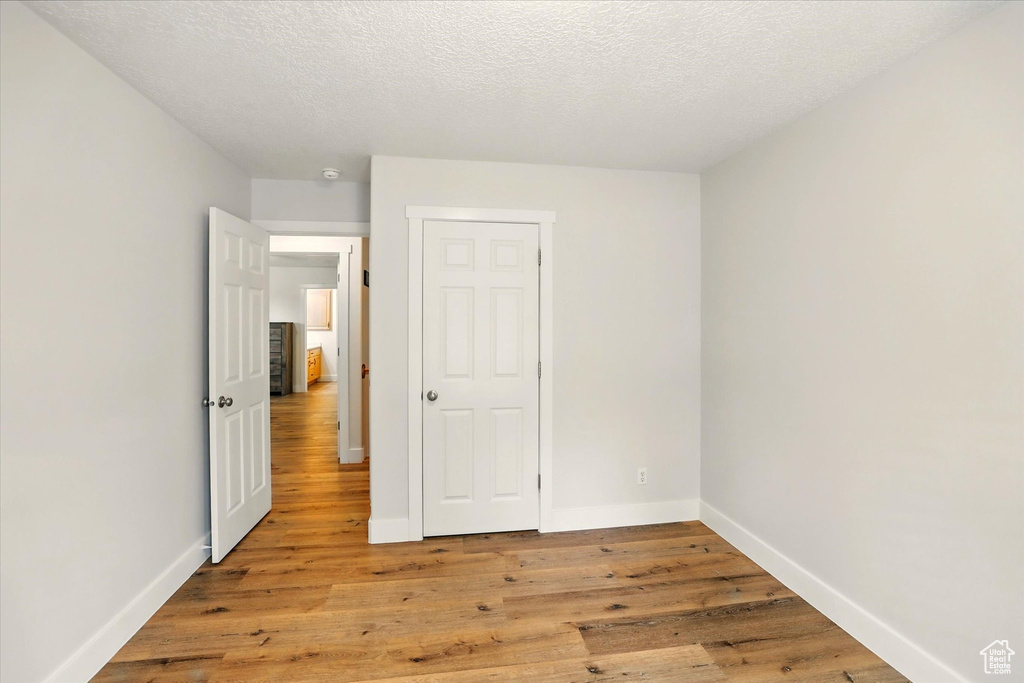 Unfurnished bedroom with light wood finished floors, baseboards, and a textured ceiling