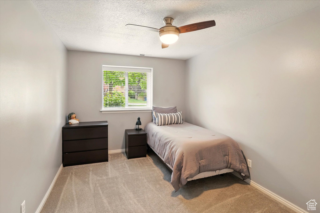Bedroom with a textured ceiling, carpet, baseboards, and a ceiling fan