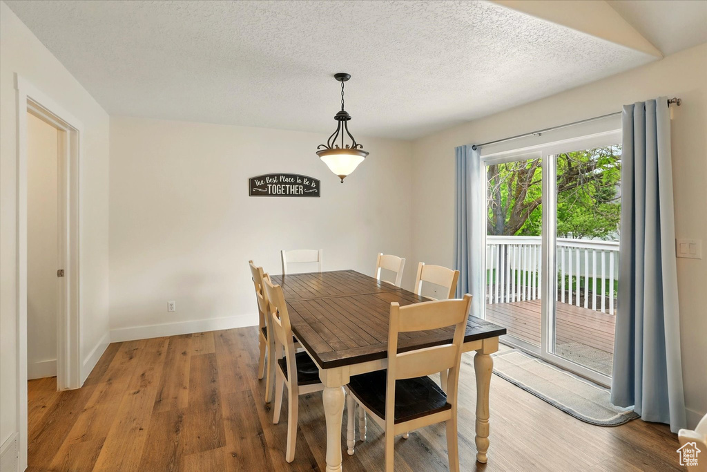 Dining room with light wood-style floors, baseboards, and a textured ceiling