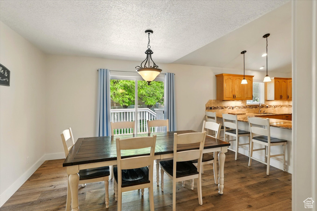 Dining room featuring a textured ceiling, dark wood-type flooring, and baseboards